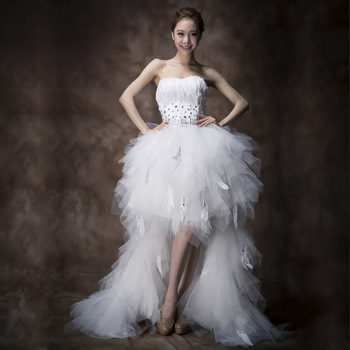 Elegancka suknia ślubna bez ramiączek z długim tyłem, ozdobiona piórami i falbanami